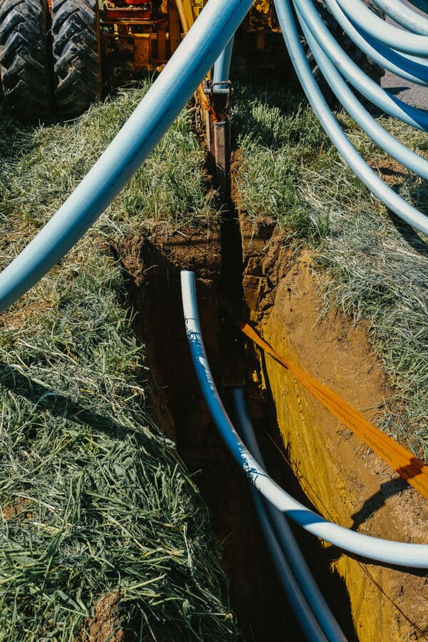 Die Pflugmaschine verlegt die Kabel im vorbereiteten Schlitz auf dem Feld ein