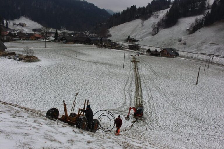 Inmitten eines verschneiten Feldes arbeitet die Firma Grabenlos AG mit einer robusten Einpflügmaschine beharrlich daran, Kabel einzubetten. Diese spezialisierte Maschine ist darauf ausgerichtet, Leitungen oder Kabel in den Boden zu verlegen,